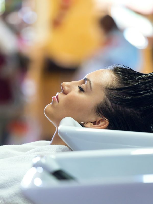 Beautiful young woman washes hair in a beauty salon.